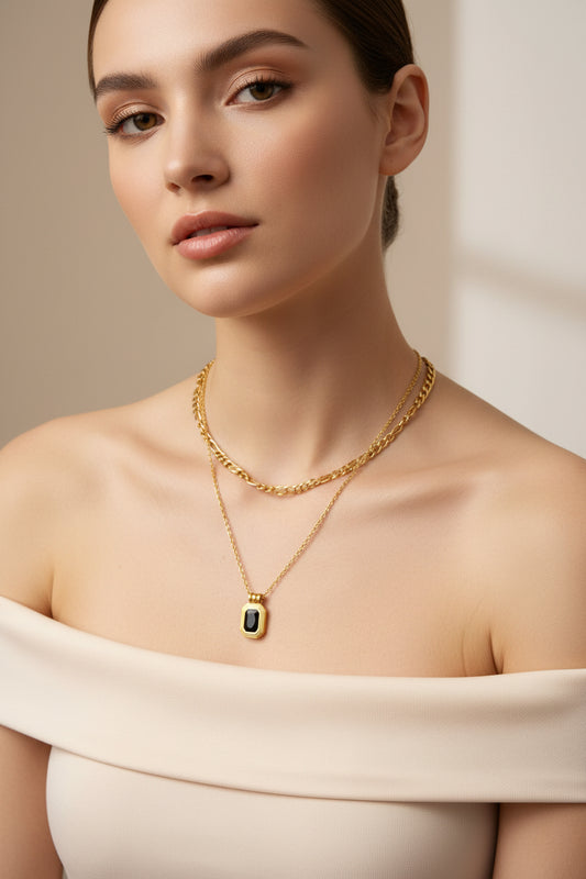 Model wearing an 18k gold plated layered necklace featuring a black pendant and a chunky chain.