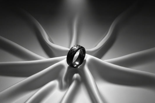 Elegant black stainless steel ring featuring a woven design on a soft satin backdrop