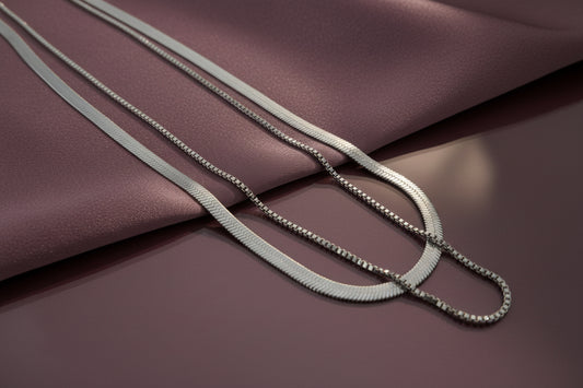 Elegant dual layer silver chain necklace displayed on soft fabric surface in muted tones