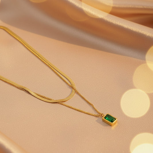 Elegant emerald layered necklace gold plated with a green gem pendant on a soft background