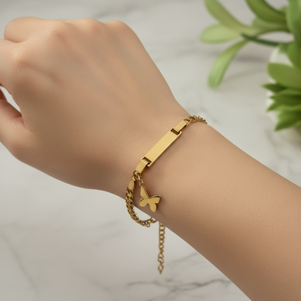 Gold chain butterfly bracelet with a dangling butterfly charm on marble background
