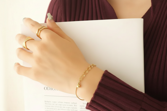 Elegant Lustre of Love Orb and Link bracelet worn with stylish rings and holding a book