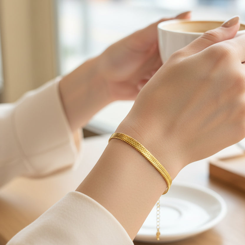 Elegant 14k gold plated snake chain bracelet worn elegantly on a wrist with a coffee cup