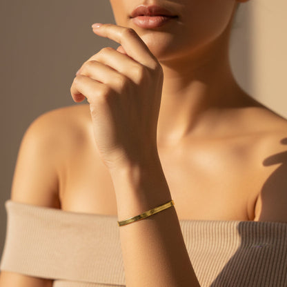 Elegant 14k gold plated snake chain bracelet worn on a woman's wrist with a stylish top