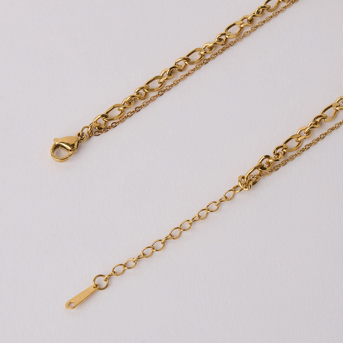 Close-up of an 18k gold plated layered necklace showcasing intricate chain details and lobster clasp