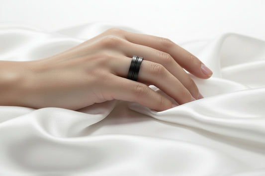 Elegant black stainless steel ring displayed on a model's hand resting on silky fabric