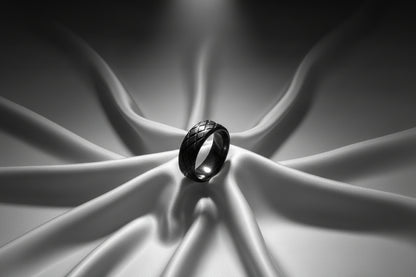 Elegant black stainless steel ring featuring a woven design on a soft satin backdrop