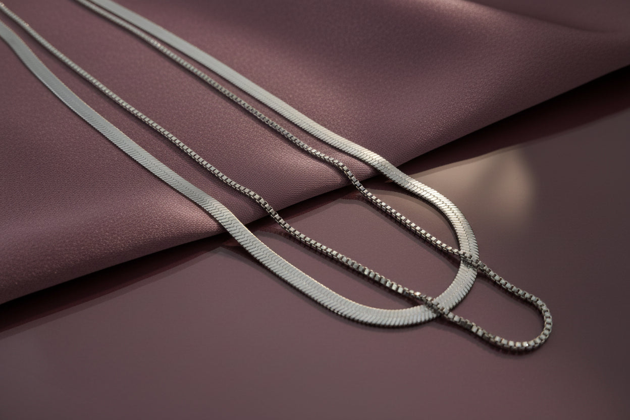 Elegant dual layer silver chain necklace displayed on soft fabric surface in muted tones