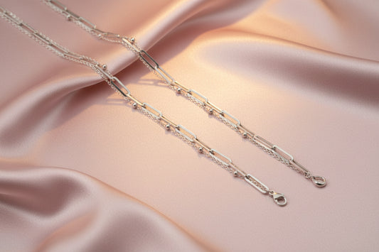 Elegant dual layer silver paperclip chain bracelet on soft satin fabric backdrop