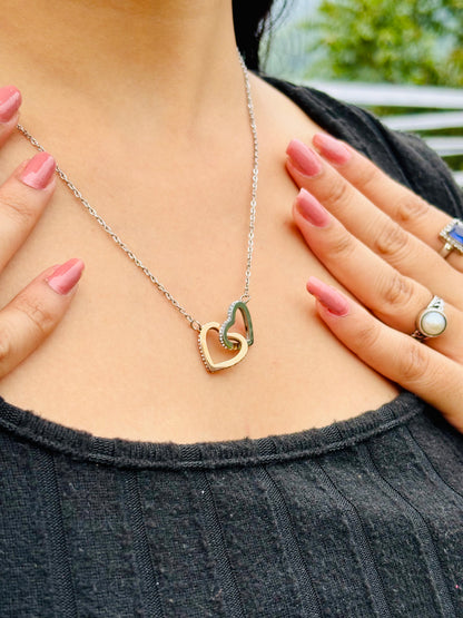 Silver chain interlock hearts necklace with gold and silver heart pendants worn on a person