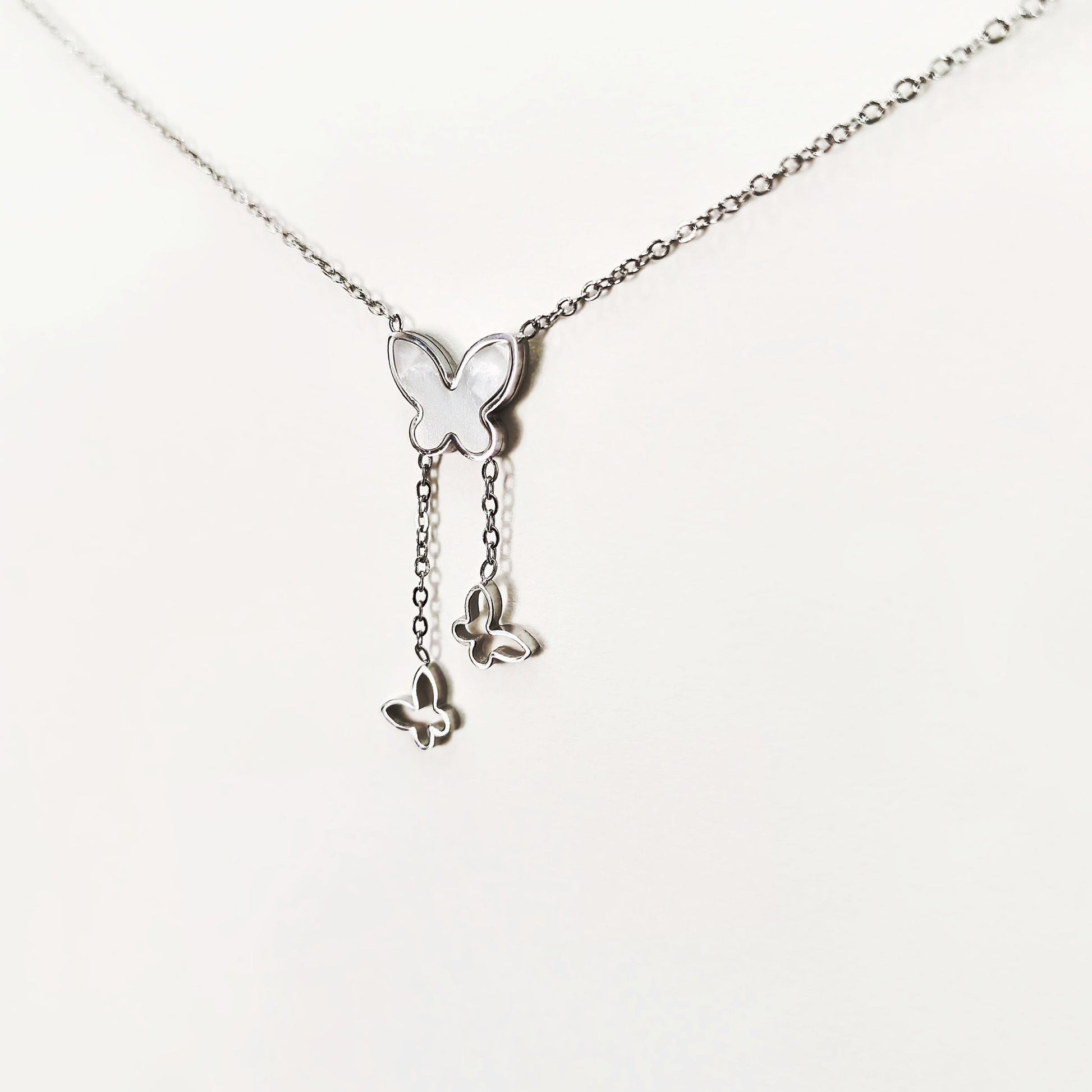 Silver butterfly pendant necklace with three butterfly charms hanging from delicate chain