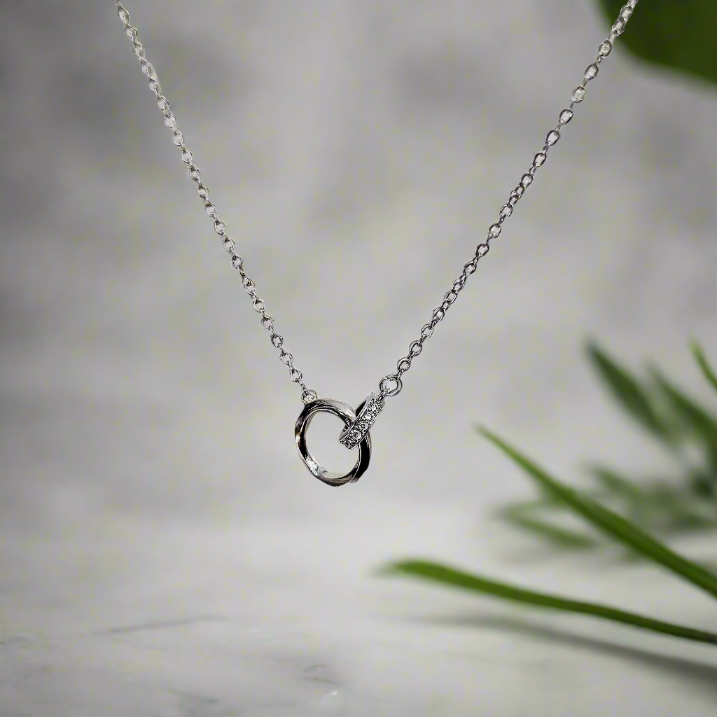 Lustre of Love silver interlocked ring pendant necklace with delicate chain on blurred background