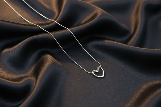 Lustre of Love silver knot heart pendant necklace on black satin fabric