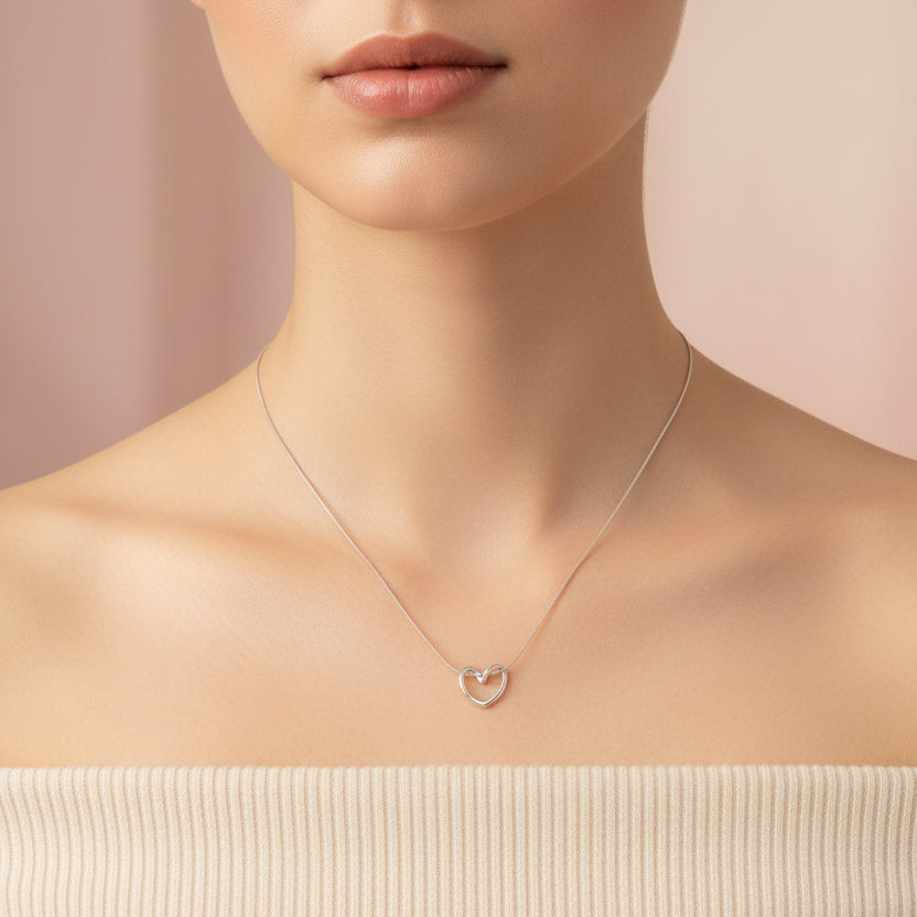 Elegant silver knot heart pendant necklace displayed on a model's neck with a soft background