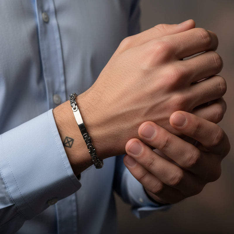 Silver-toned Byzantine bracelet worn by a man with a light blue shirt, showcasing intricate design details