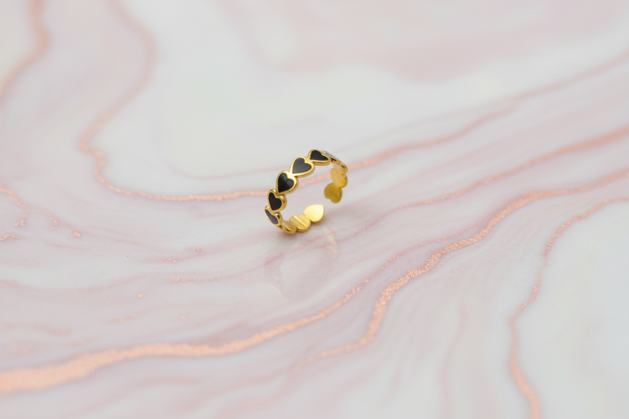 Lustre of Love stainless steel adjustable size ring with black heart design on a marble background