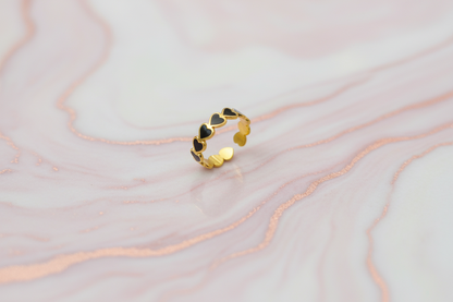 Lustre of Love stainless steel adjustable size ring with black heart design on a marble background