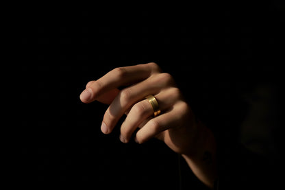 Elegant stainless steel gold ring for men showcased on a hand against a dark background