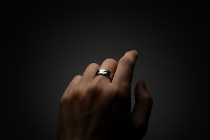 Stylish stainless steel silver ring for men worn on a hand against a dark background