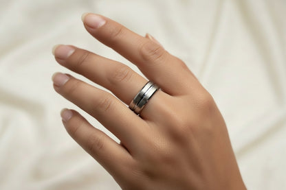 Elegant stainless steel silver ring for men worn on a finger against a soft fabric background
