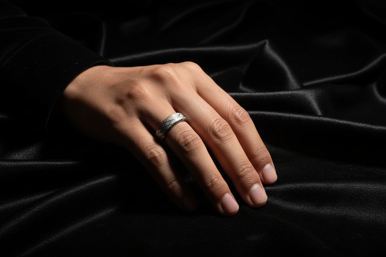 Stylish stainless steel silver ring on a hand placed on soft black fabric