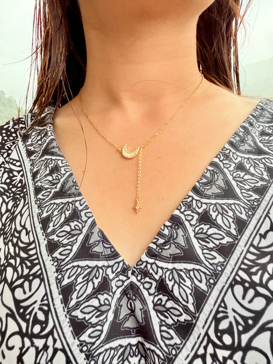 Gold moon pendant necklace with dangling star charm by Lustre of Love worn with patterned black and white top